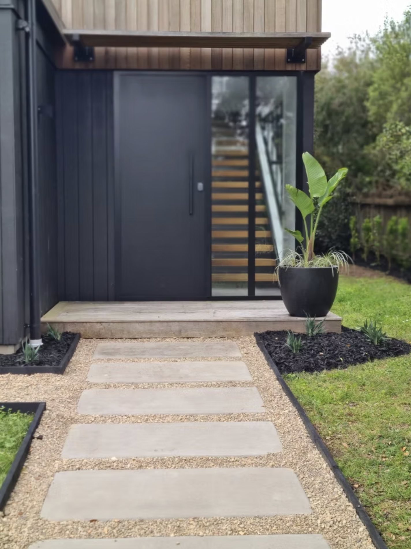 A modern entrance with a paver path and specimen palm